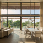 Double-height living room with glass wall onto the lake and pool