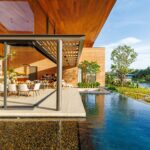 Open-cornered living pavilion beside the pool at the lake edge