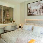 Modern luxury bedroom with desk, neutral tones, and artwork above bed