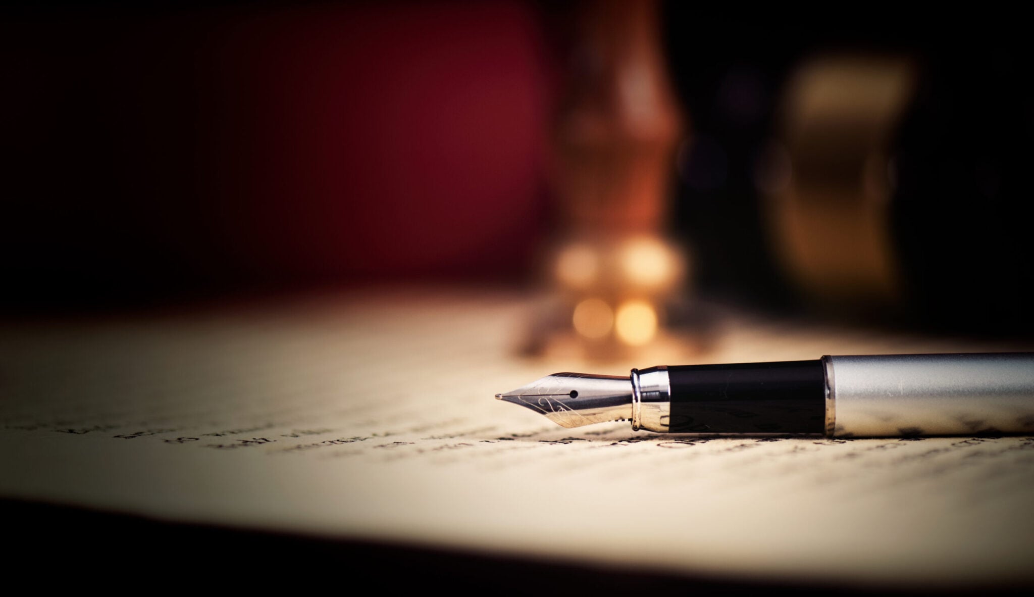 A fountain pen resting on a printed contract in low light, illustrating the contract and transfer stages of buying property in Phuket.